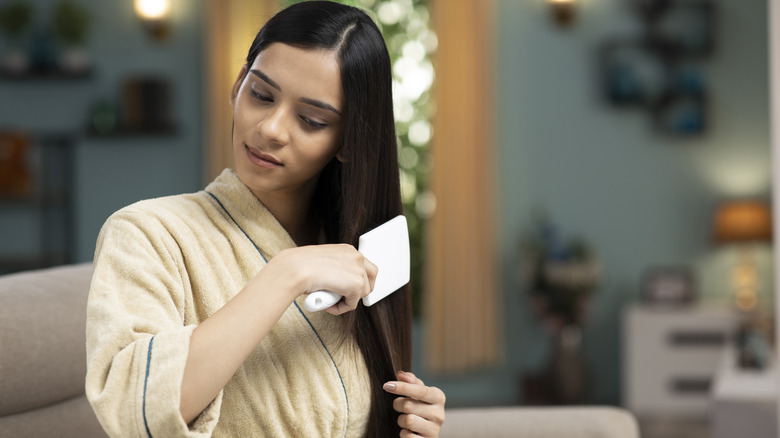 woman brushing long healthy hair 