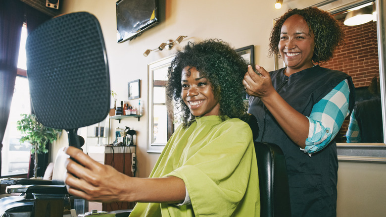 Woman checking her hair in a handheld mirror