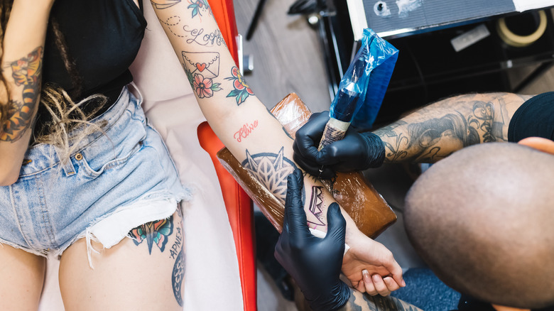 Woman getting her arm tattooed