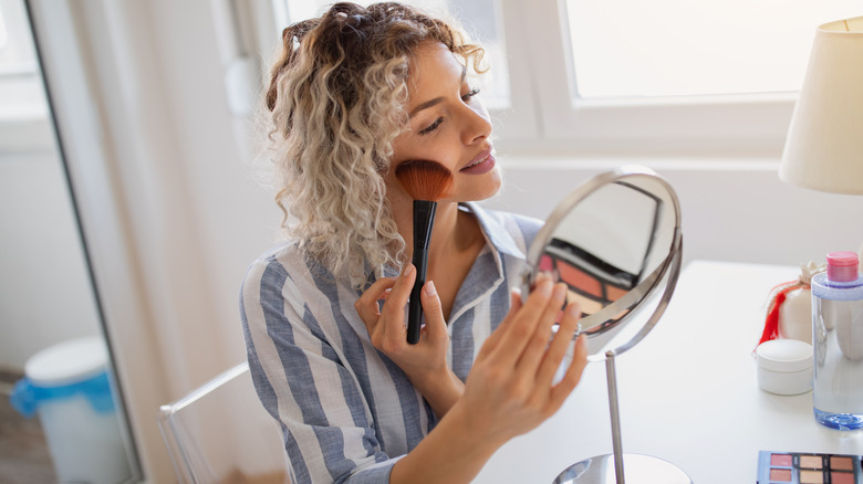 Woman applying makeup fluffy brush