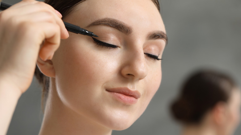 Woman applying liquid eyeliner