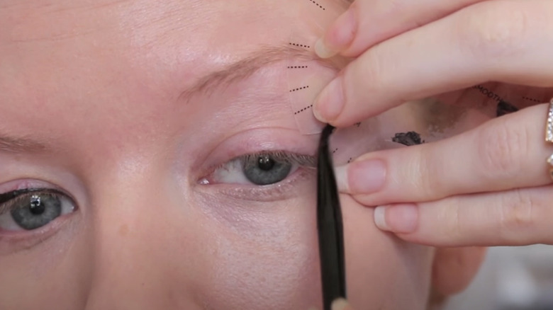 Woman using stencil for eyeliner