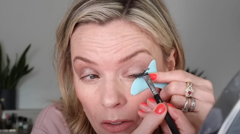 Woman drawing eyeliner with a stencil