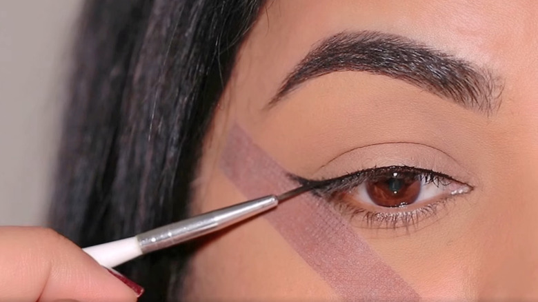 Woman using tape to draw eyeliner