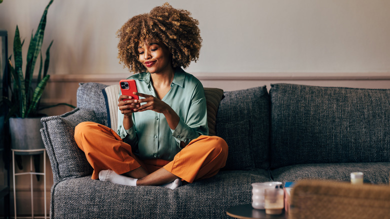 woman sitting on couch on smartphone 