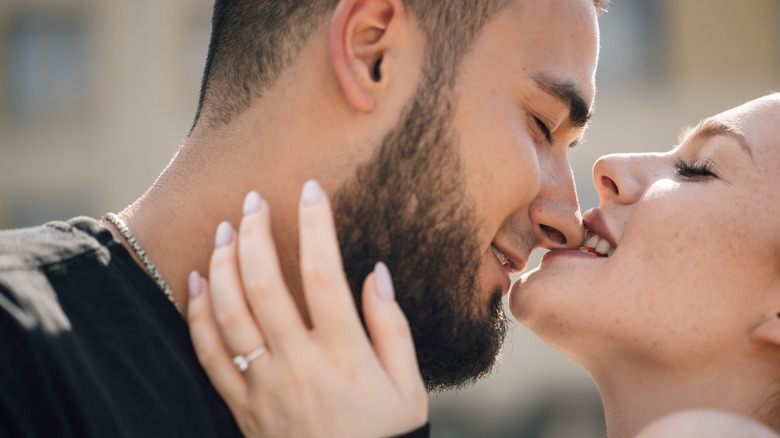 A woman playfully biting her partner's nose.