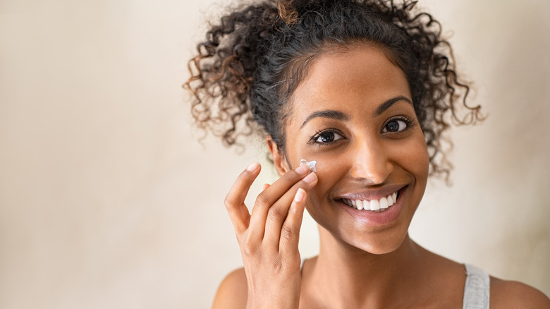 Woman applying moisturizer to face.