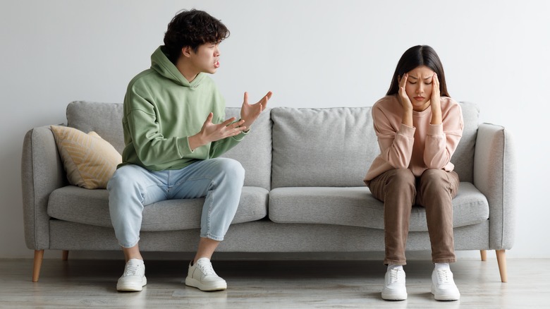 A stressed woman sitting away from the man talking to her.