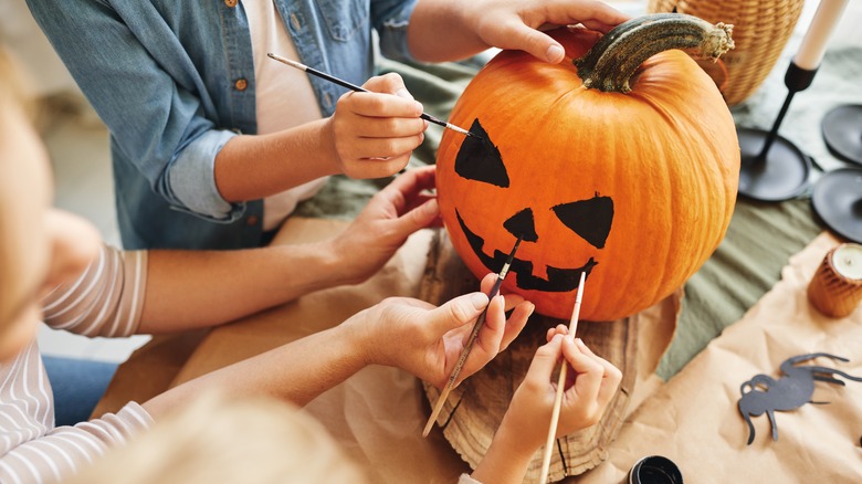 Group of people painting pumpkin at gathering