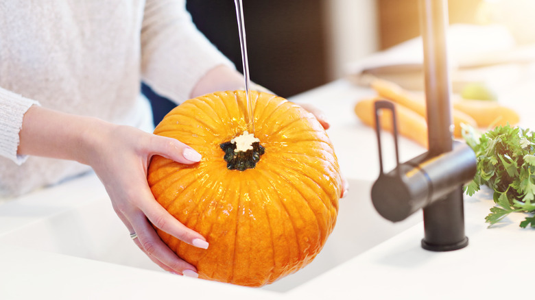 Woman rinsing pumpkin in kitchen sink