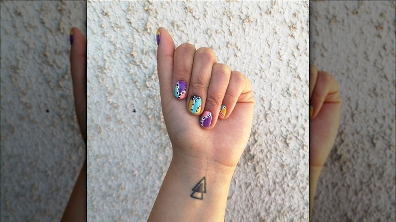 hand with mismatched geometric cow print nails