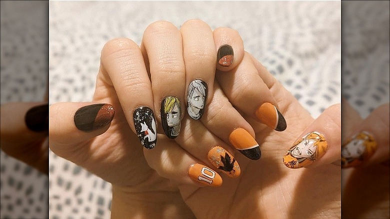 womans hands with mismatched anime manicure