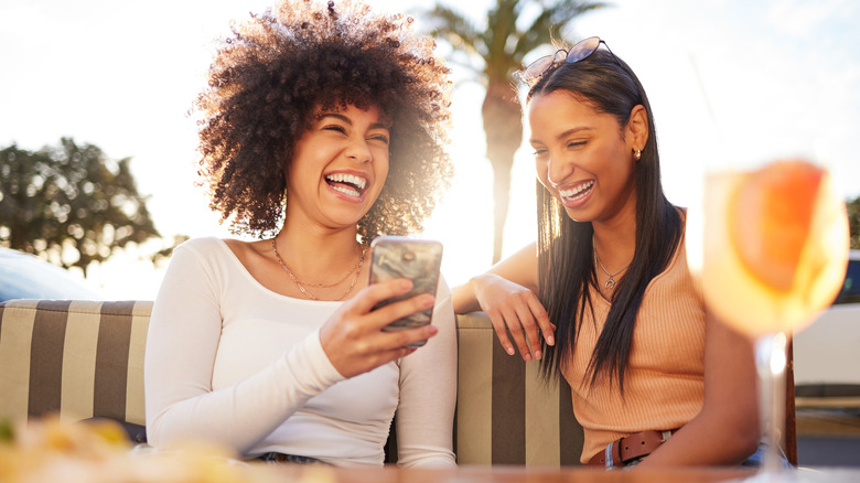 laughing texting woman with friend