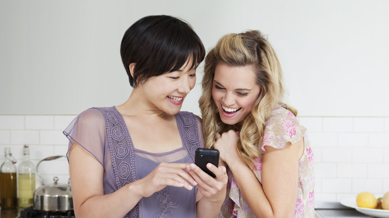 laughing texting woman with friend