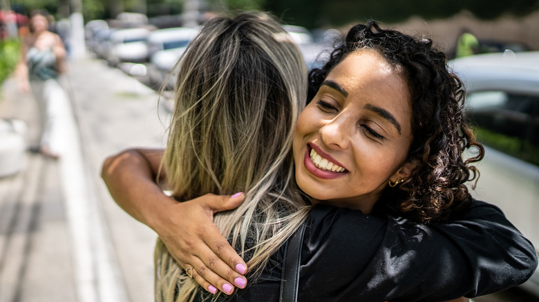 Two women hugging in the street.