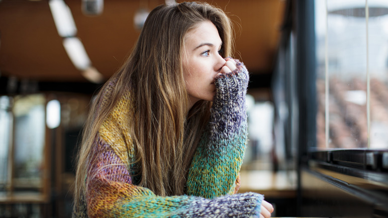 An anxious woman staring out a window.