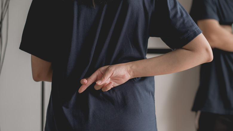 A woman crossing her fingers behind her back.