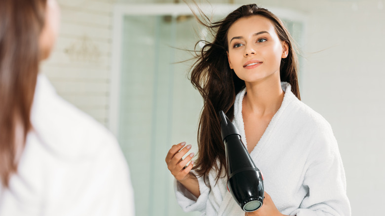 Woman blow-drying hair in mirror