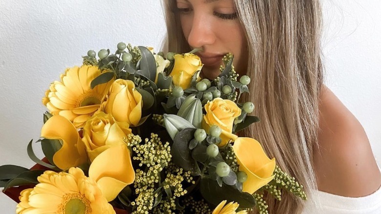 Woman smelling bouquet of yellow flowers 