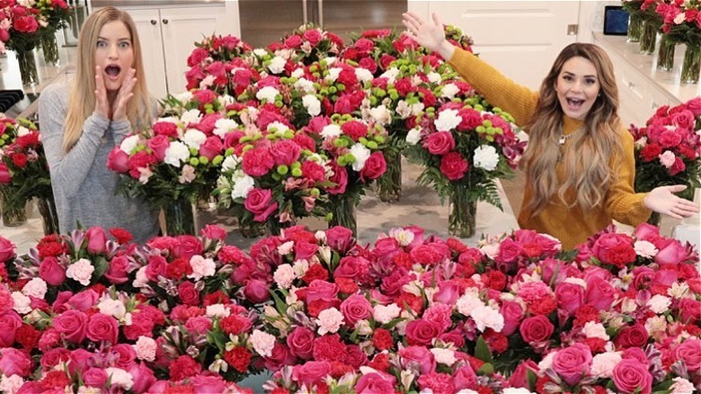 Two women standing among lots of flowers 