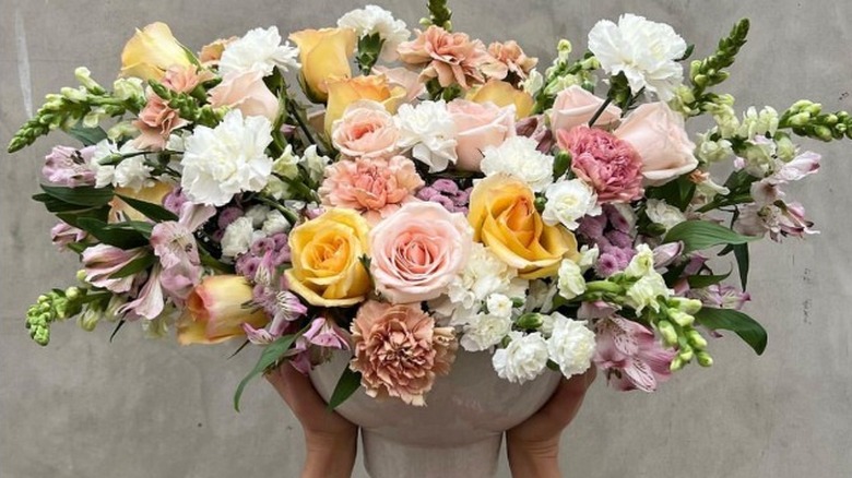 Hands holding up a floral arrangement 