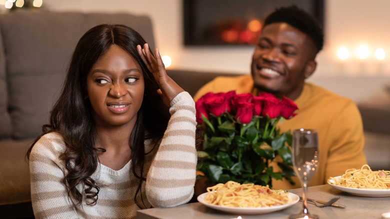 A man trying to give his disappointed girfriend roses and a pasta dinner.