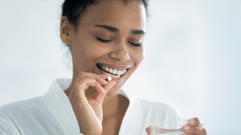 Woman taking zinc supplement with glass of water