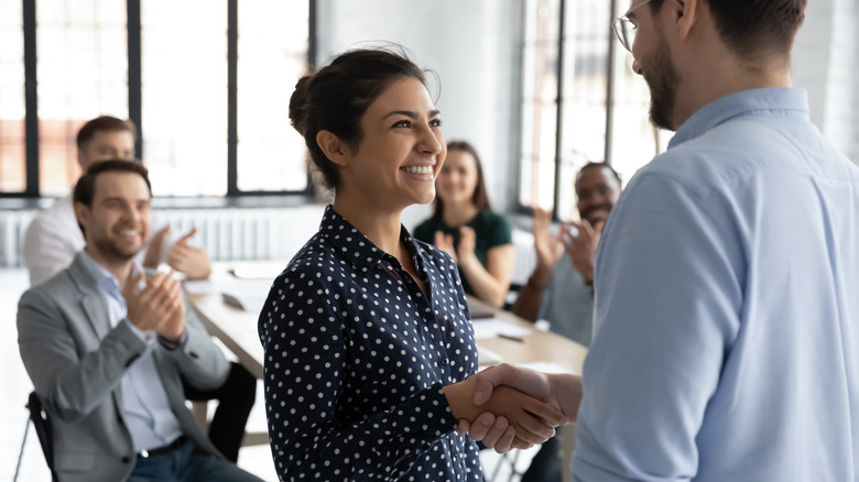 Woman receiving applause from coworkers