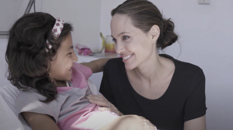 Angelina Jolie wears minimal makeup as she sits with a little girl in hospital.