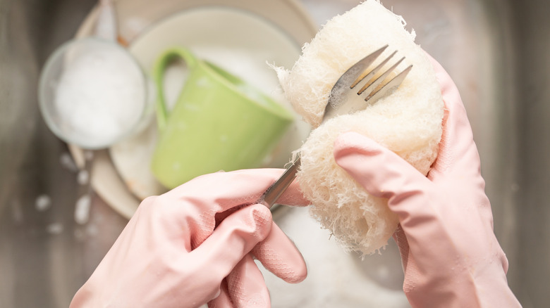 Washing dishes while wearing pink gloves