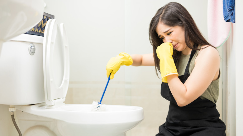 Woman cleaning toilet bowl