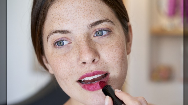 Woman applying pink lipstick