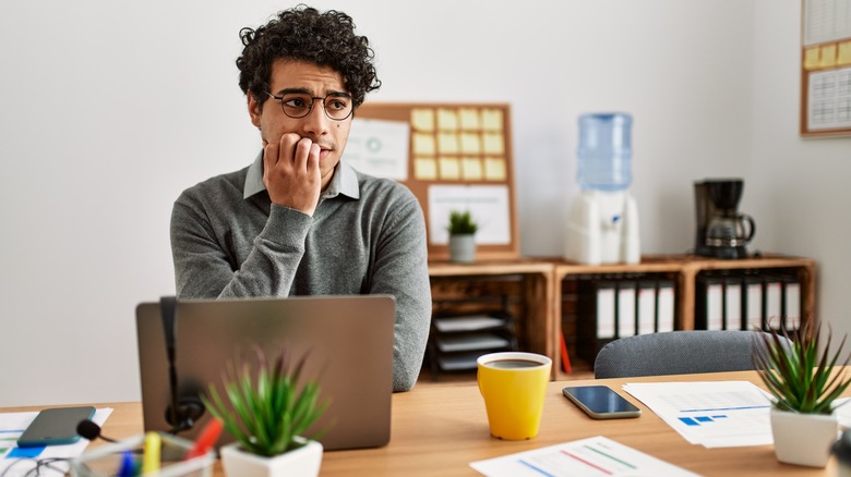 man biting nails while working