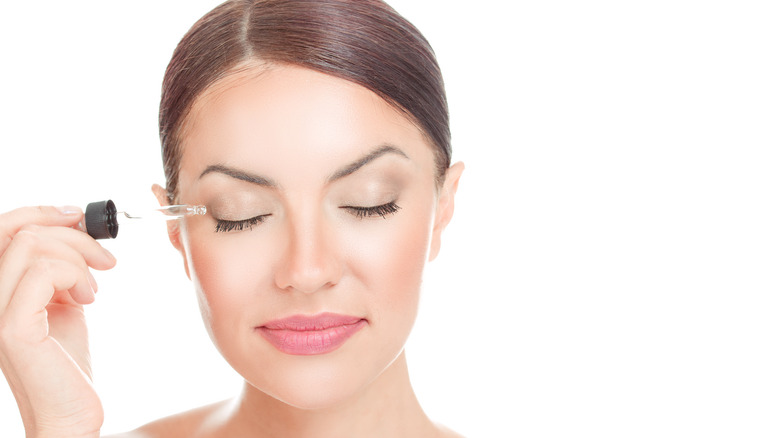 woman applying serum to eyelashes