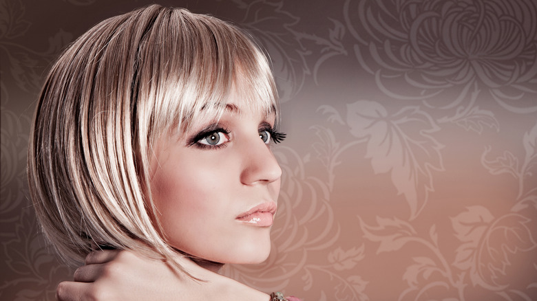 A woman posing with a blond pageboy bob.