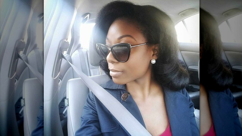 A woman wearing sunglasses posing in the car with vintage hair.