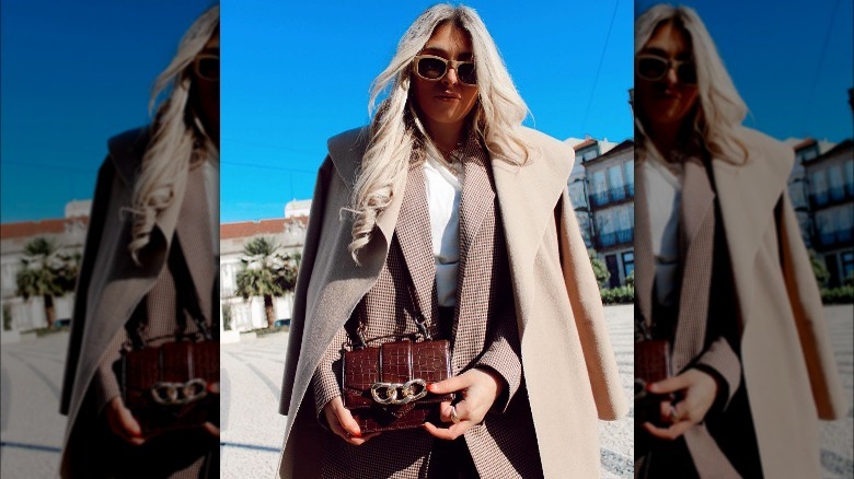 Woman poses with brown handbag