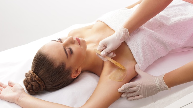 Woman having armpit waxed 