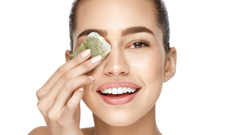 woman holding tea bag to eye