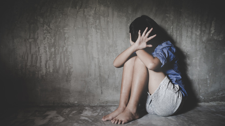 Young woman hiding in damp basement