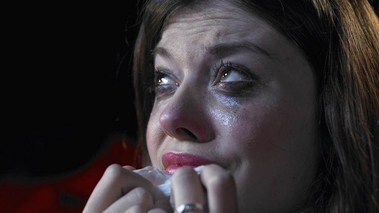 Terrified woman crying into tissue