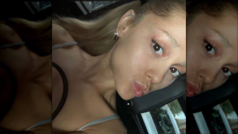A blonde Ariana Grande taking a car selfie