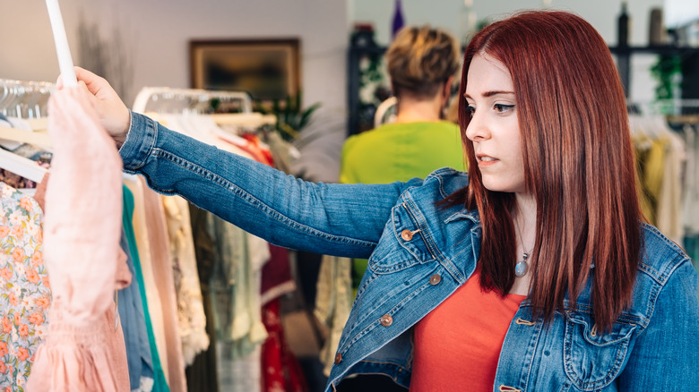 woman with red hair looking at pink shirt