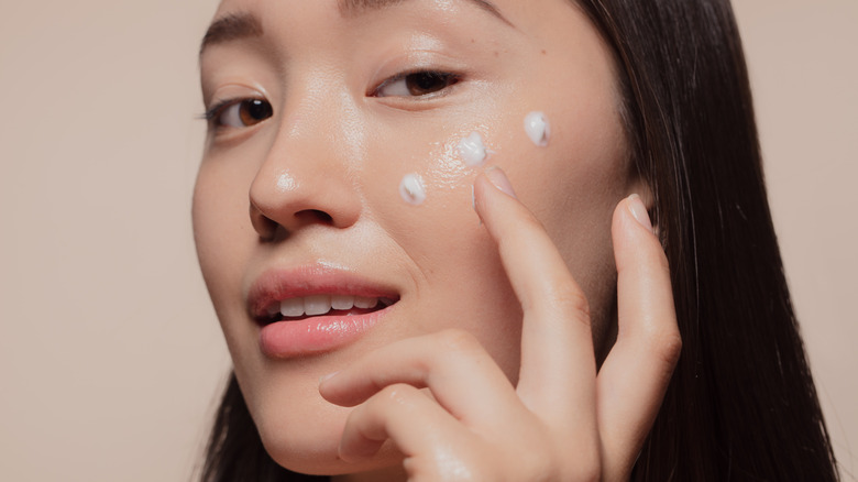 Woman applying cream to her face