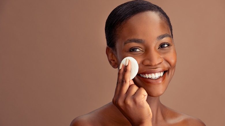 Woman cleaning her face with a cotton pad