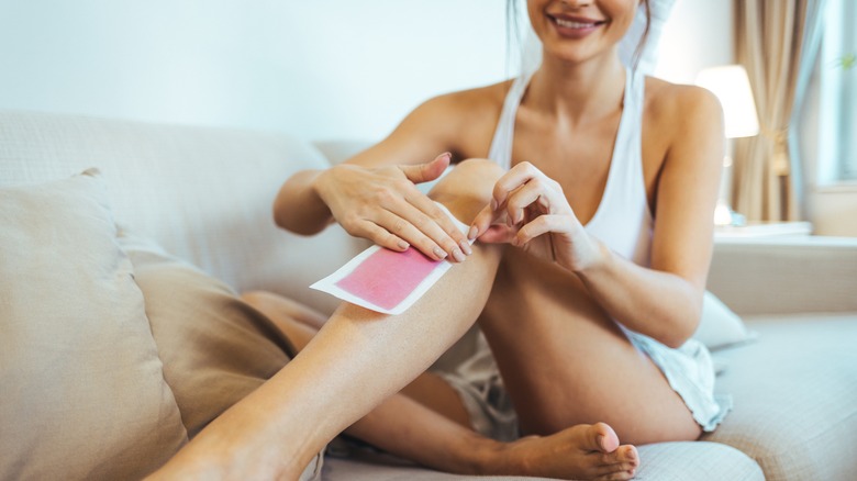 Woman waxing leg with wax strip