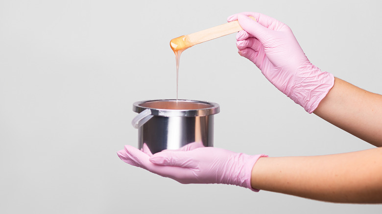 Wax pot with wooden spatula covered in wax