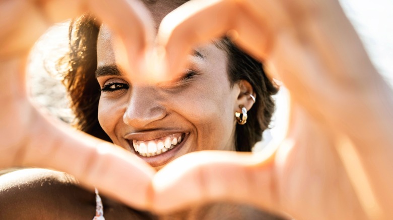 Close up of young woman making heart gesture with hands