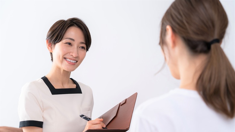 Woman with back to camera facing smiling therapist with clipboard