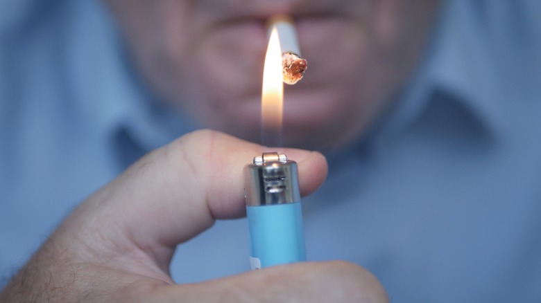 Close up of older man lighting cigarette with gas lighter